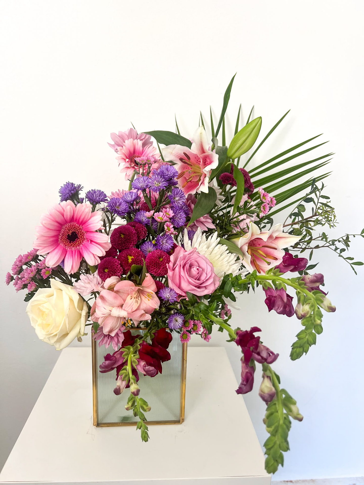 Pink and lilac arrangement with gerbera, lilies and asters in a fluted glass vase